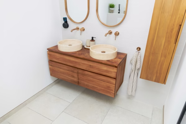 Salle de bains contemporaine avec meuble suspendu en bois, double vasque ronde, miroirs ovales et robinetterie murale dorée